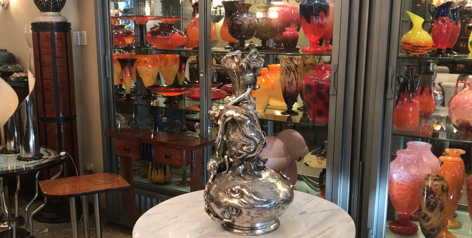 Deux vases anciens au design art nouveau dans un cadre avec d'autres objets décoratifs.