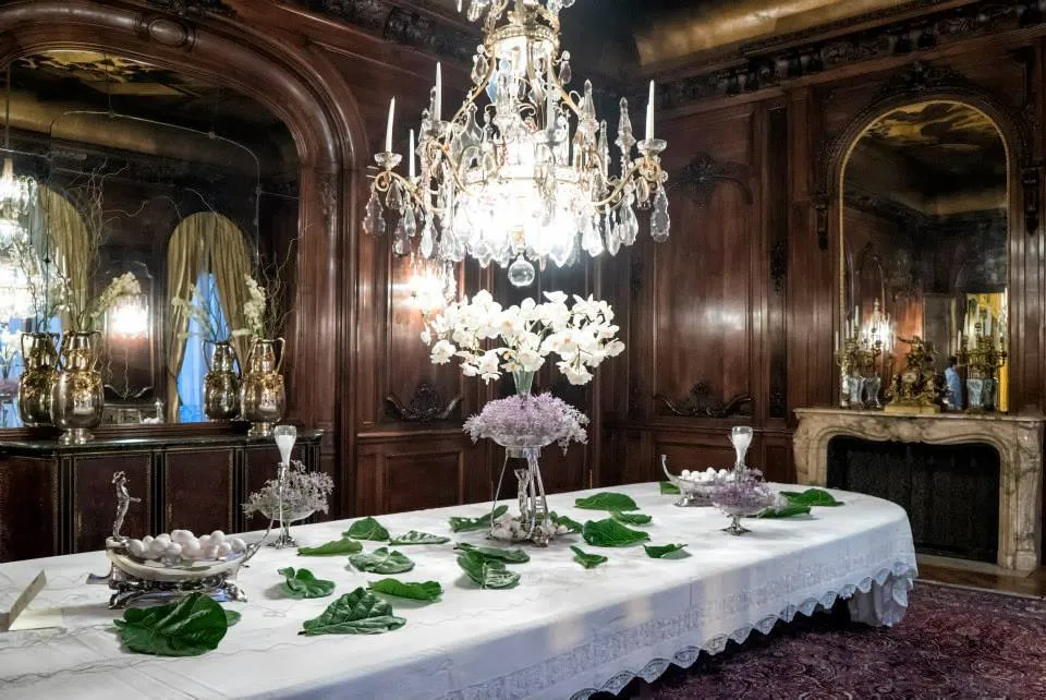 Deux vases antiques sur une table élégamment décorée avec des fleurs et des feuilles.