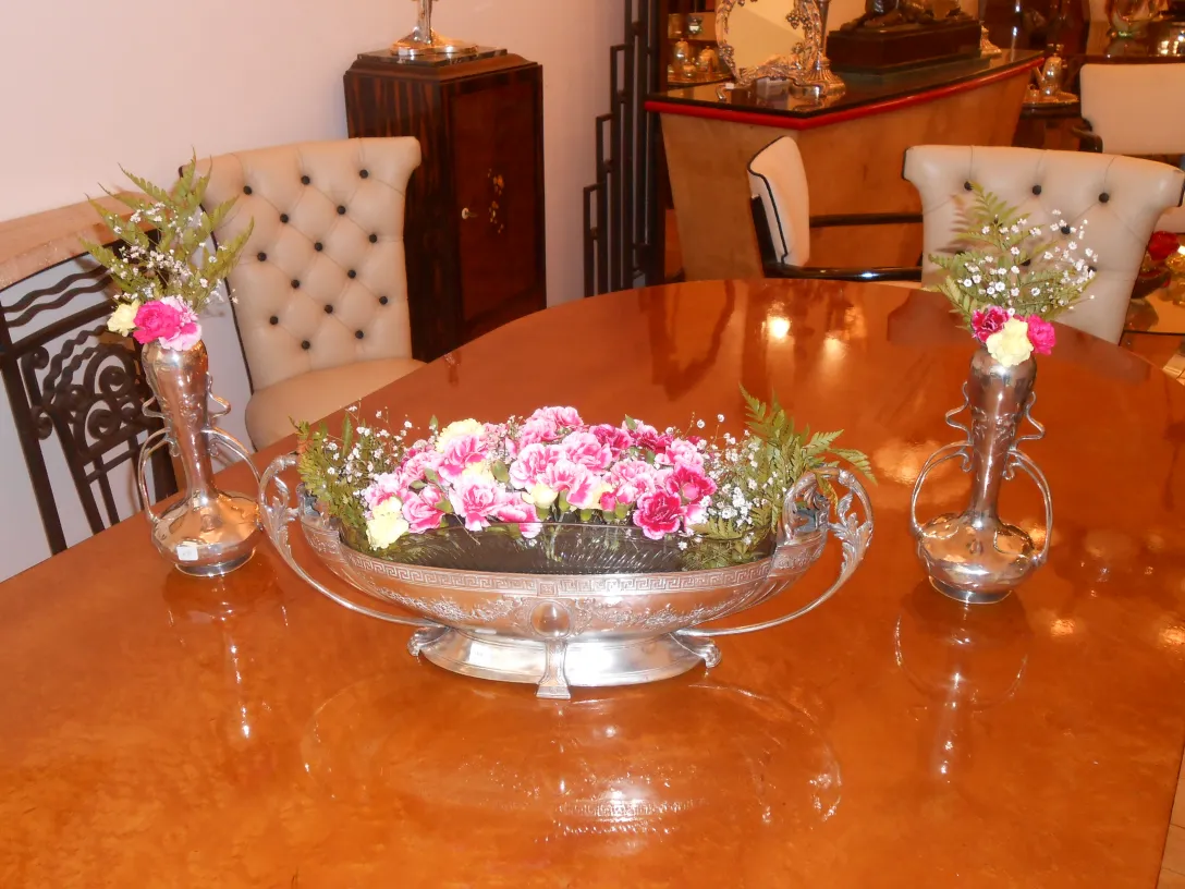 Dos antiguos floreros Art Nouveau con flores coloridas en una mesa elegante, rodeados de una decoración vintage.