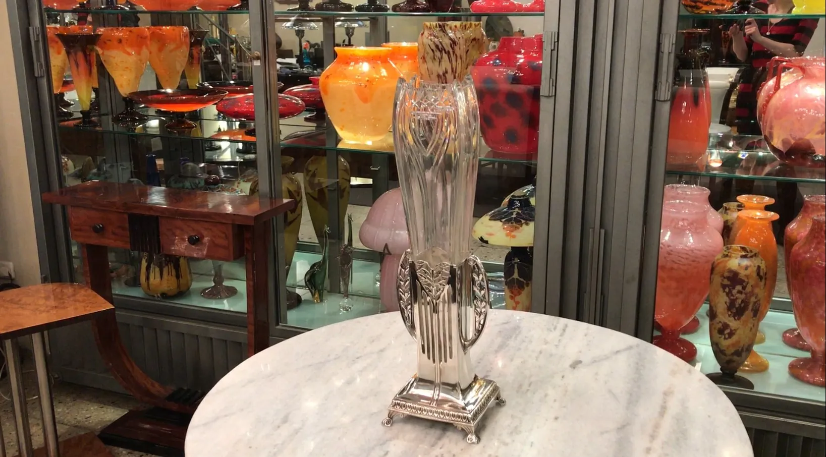 Deux vases anciens exposés dans un meuble en verre, avec un fond coloré.