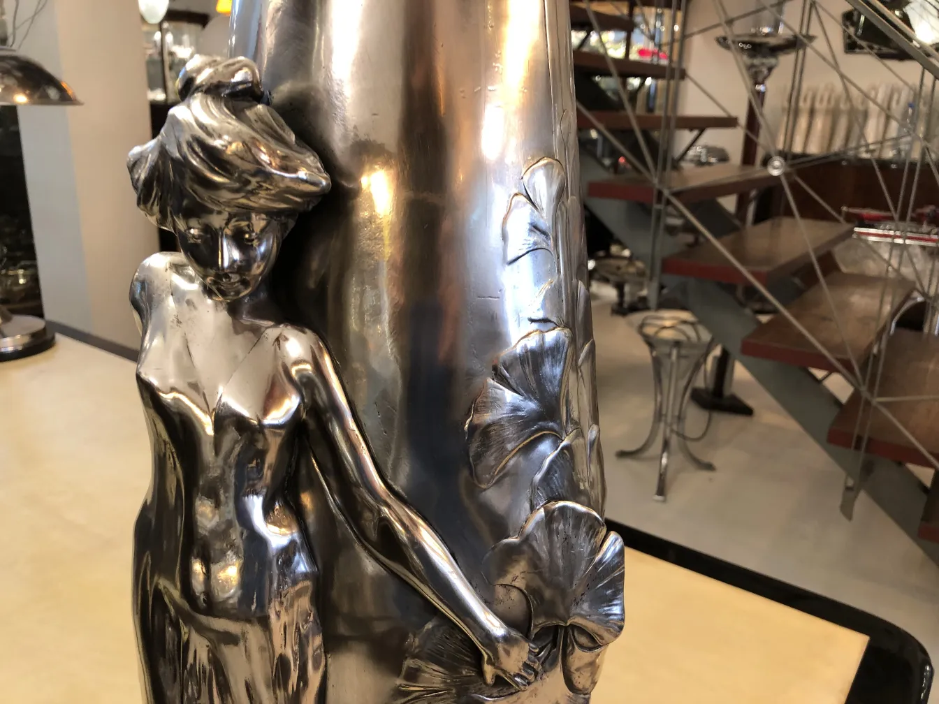 Vase ancien en métal avec une élégante figure féminine et des feuilles.