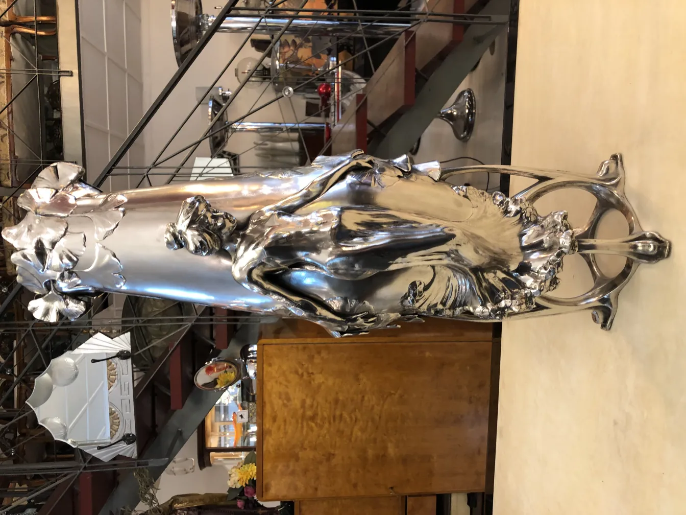 florero antiguo art nouveau con detalles en relieve y diseño de flores, fondo de antiguos muebles