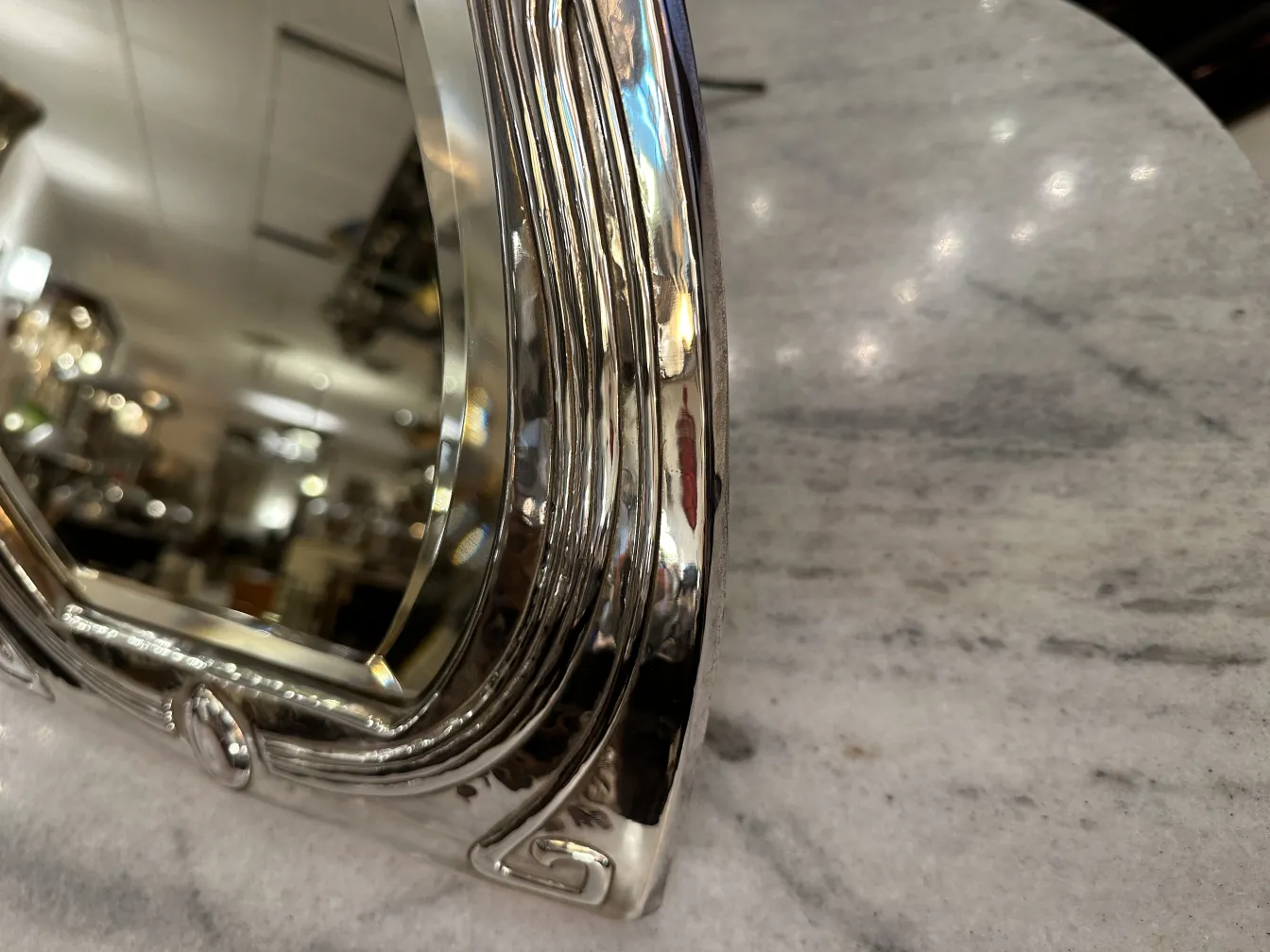 Side view of an antique Art Nouveau mirror with decorative details in an elegant setting.