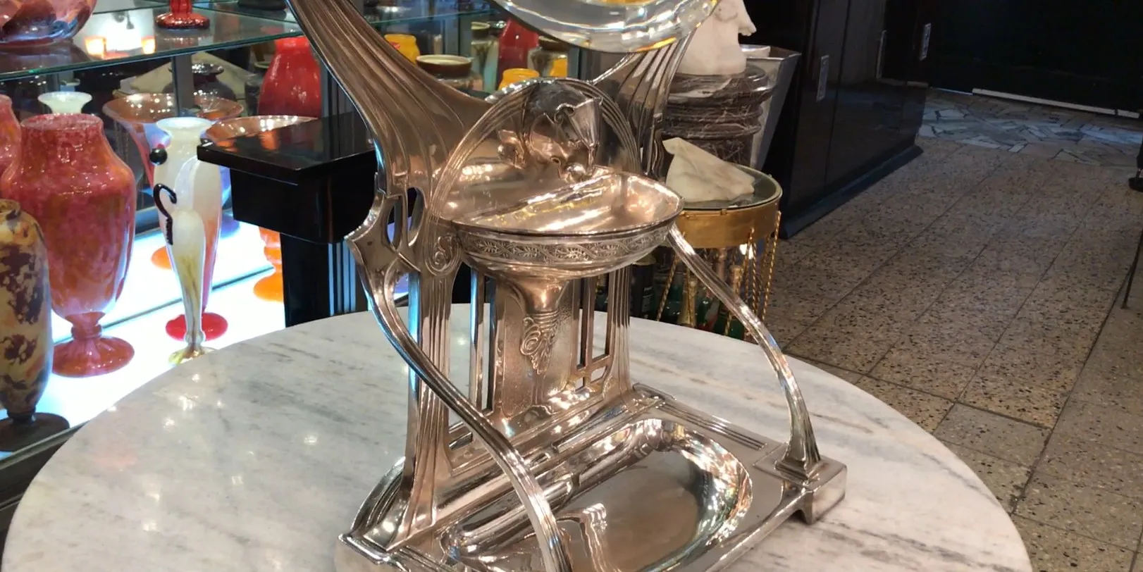 Antikes Art Nouveau Spiegel mit dekorativer Basis, umgeben von bunten Gegenständen.