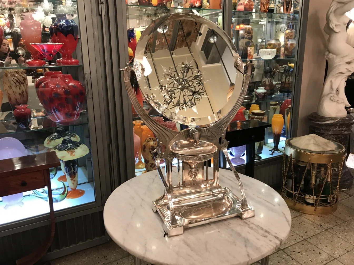 Decorative antique mirror with an Art Nouveau base, surrounded by collectibles.