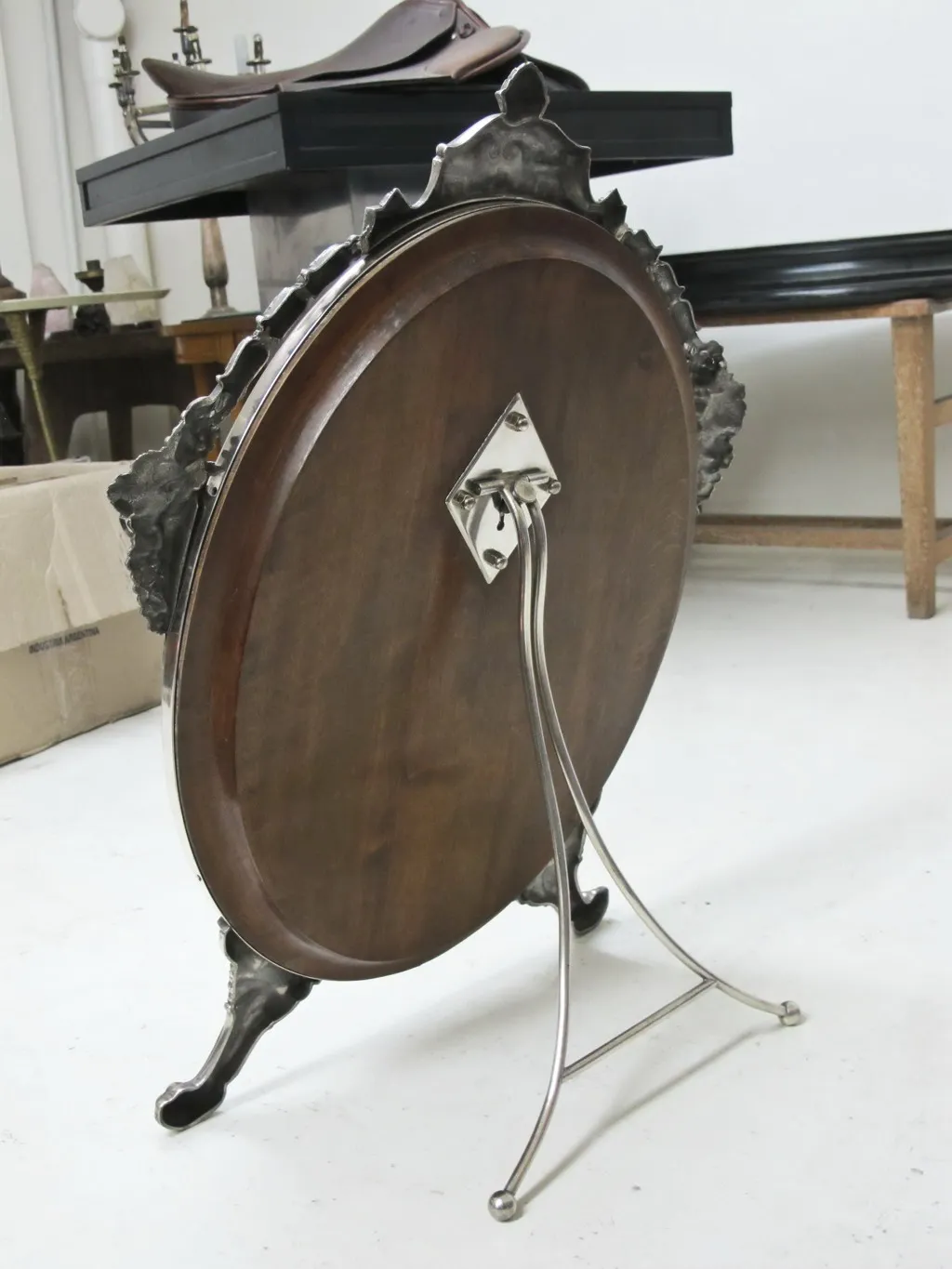 Espelho antigo com base decorativa em estilo Art Nouveau, fundo claro.