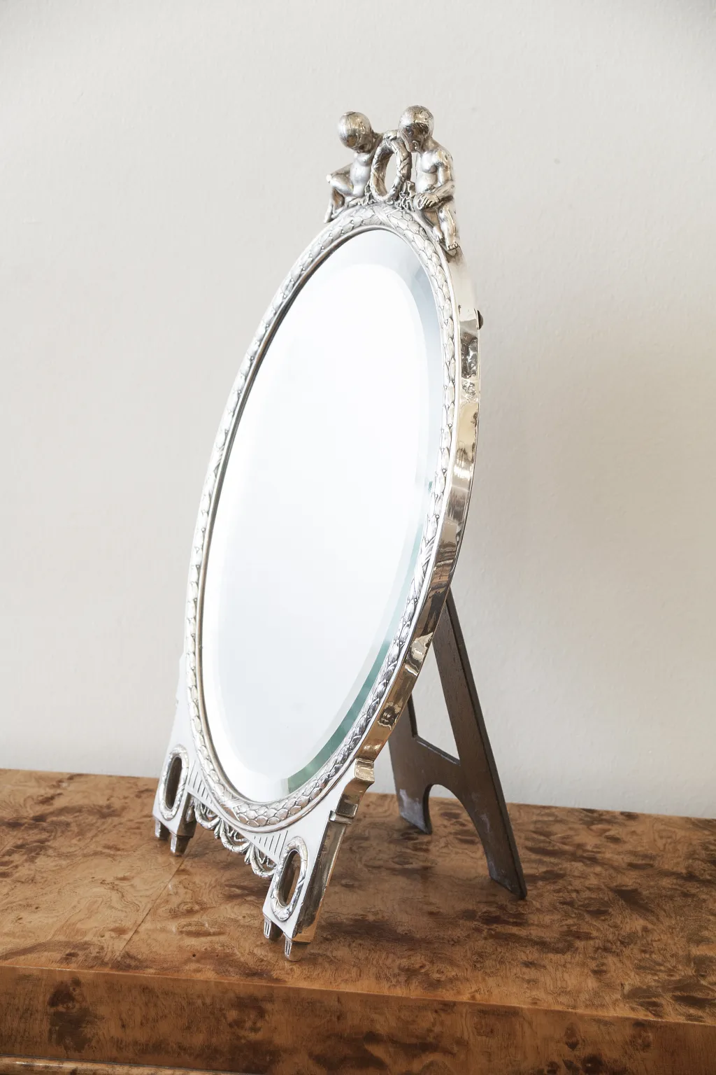 Antique oval mirror with decorative top.