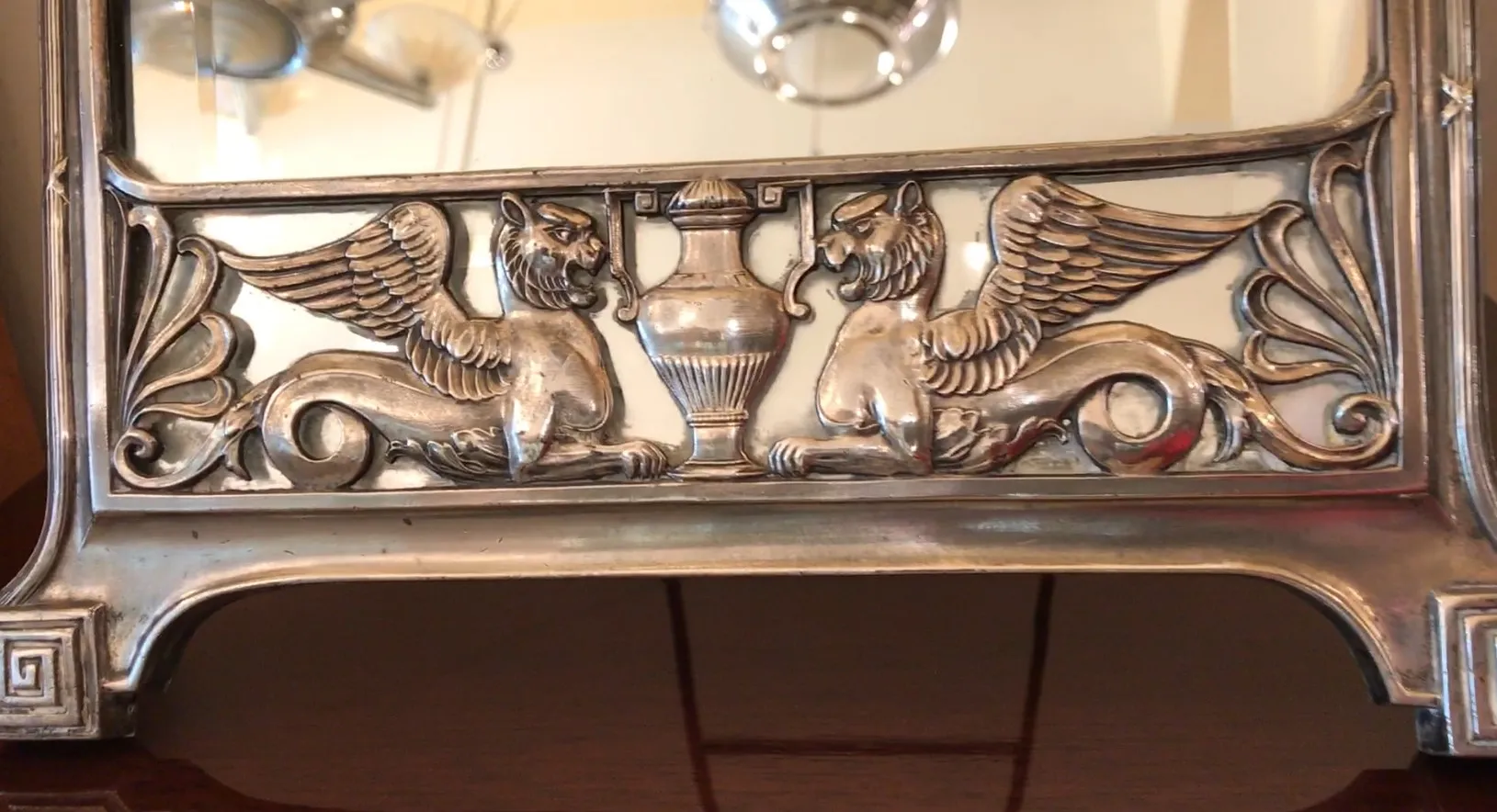 antiker Spiegel mit Verzierungen im Art-Nouveau-Stil, der eine elegante Umgebung spiegelt.