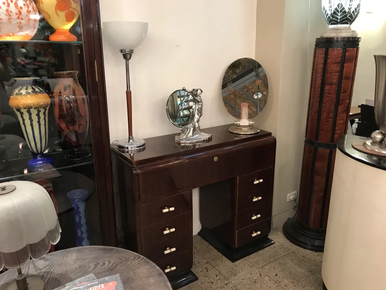 antique oval mirror with fine detailing, surrounded by lamps and vases.