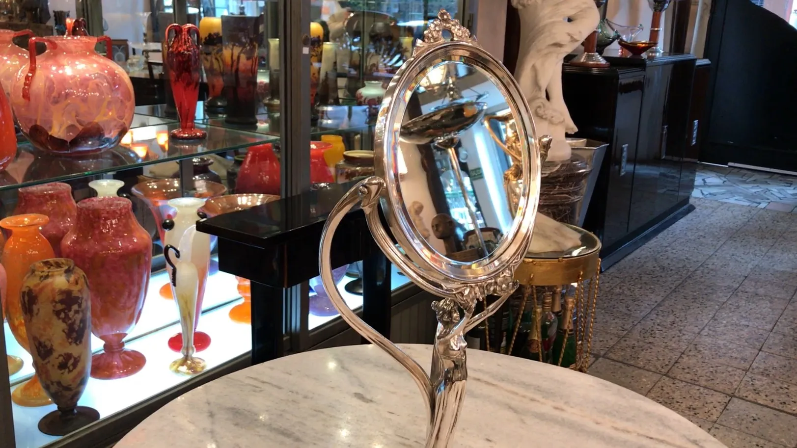 Espejo antiguo con detalles art nouveau, rodeado de objetos decorativos.