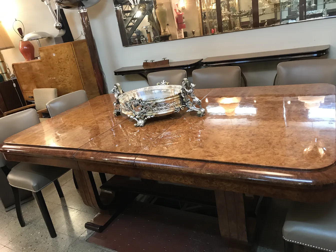 jardinera antigua Christofle en una mesa de madera, con sillas oscuras detrás.