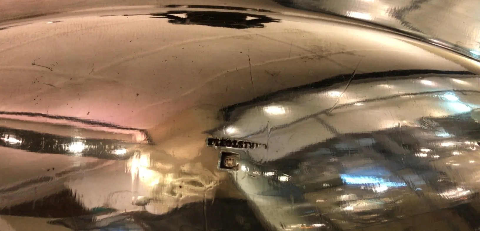 クリストフルのアンティークセンターピース、光沢のある仕上げとエレガンス、背景に柔らかな照明が装飾されている