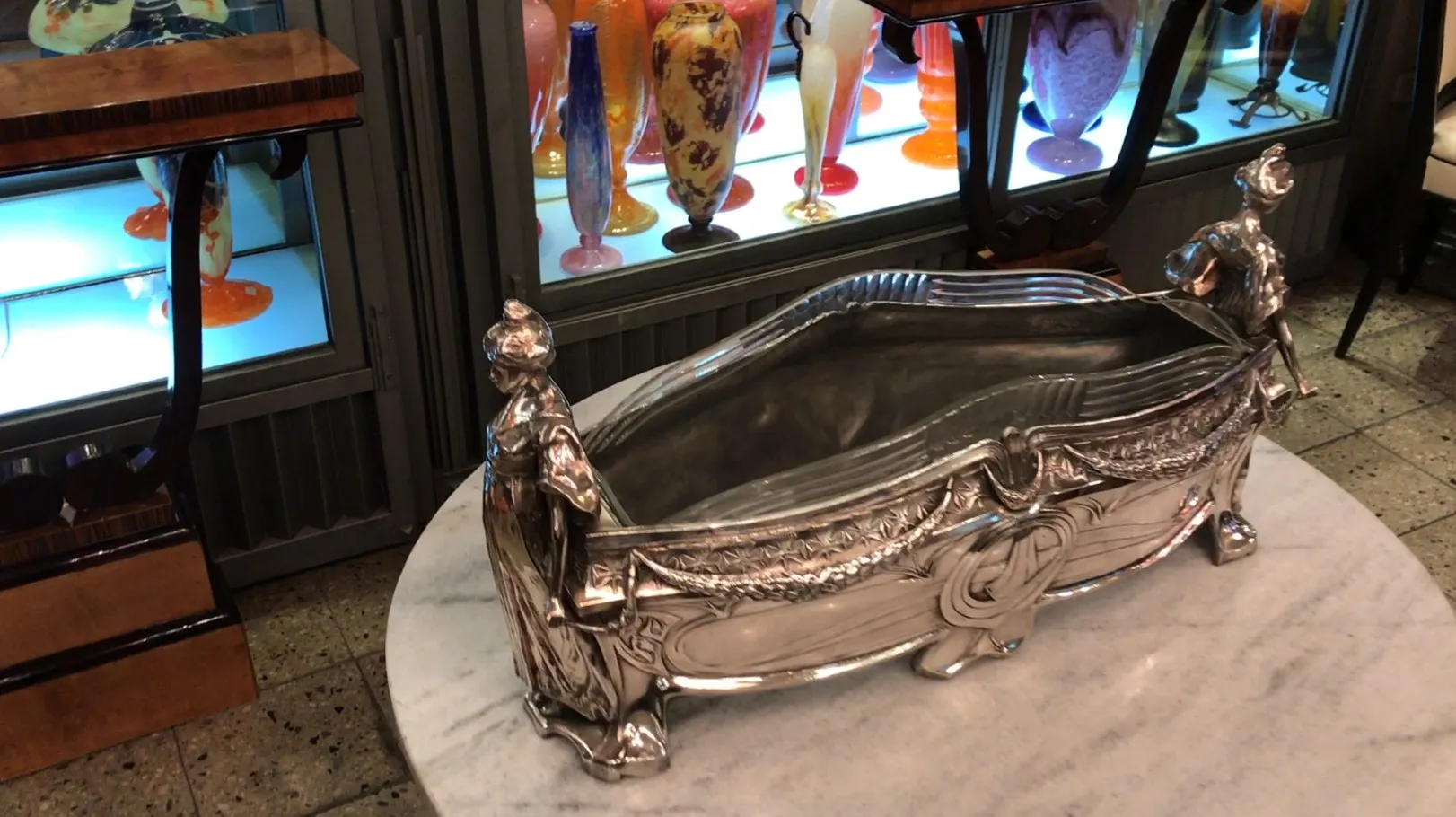 antique WMF centerpiece with decorative figures at the ends, on white surface