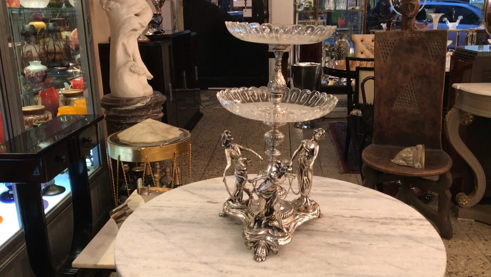antique WMF centerpiece with two levels and decorative figures, set in an elegant environment.