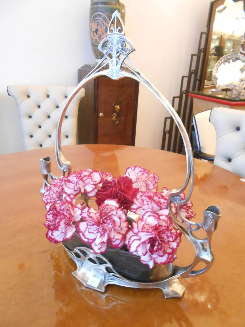 Centre de table ancien WMF avec des fleurs colorées dans un cadre élégant.