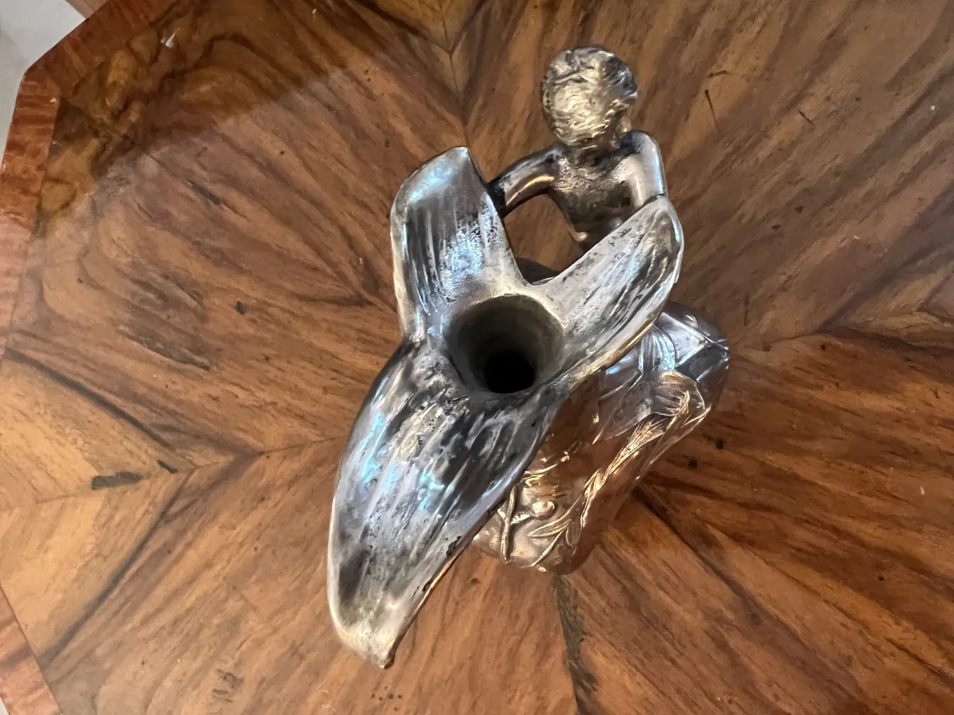 jarra antigua con una figura en la parte superior, ubicada en una mesa de madera