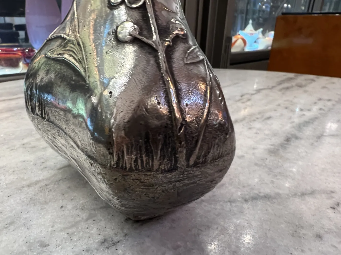 jarra antigua con detalles decorativos y un acabado brillante sobre mármol