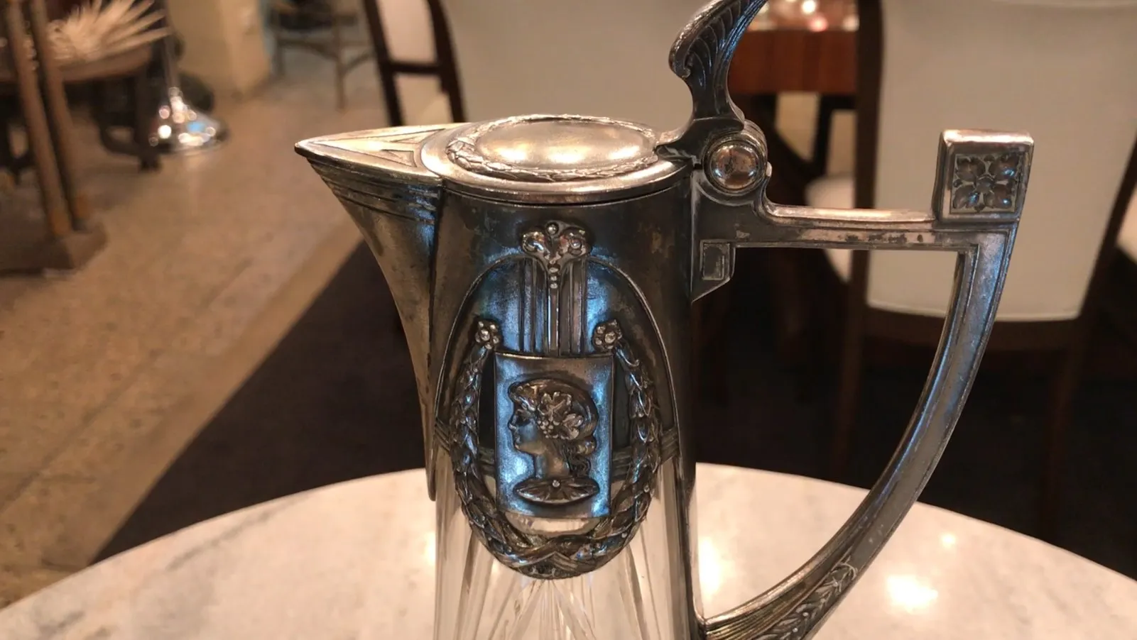 우아한 테이블 위에 놓인 오래된 WMF 주전자 두 개의 측면 보기, 배경에는 현대식 레스토랑이 있습니다.