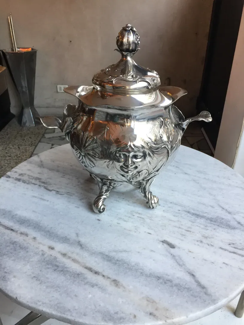 Antigua ponchera WMF con diseño floral y tapa en mesa.