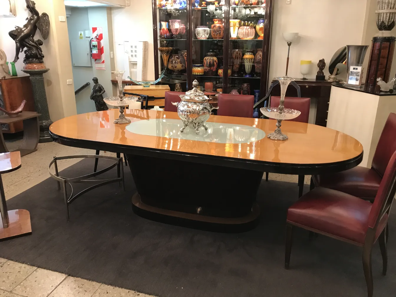 Poncheira WMF antiga em uma sala de estar elegante com móveis de madeira e cadeiras vermelhas.