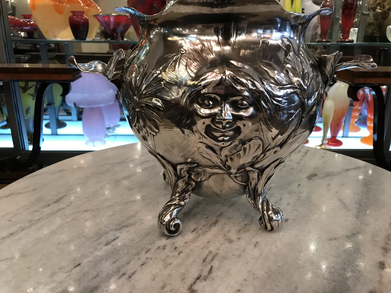Antique WMF punch bowl with ornamental details, decorative face, on a marble table.