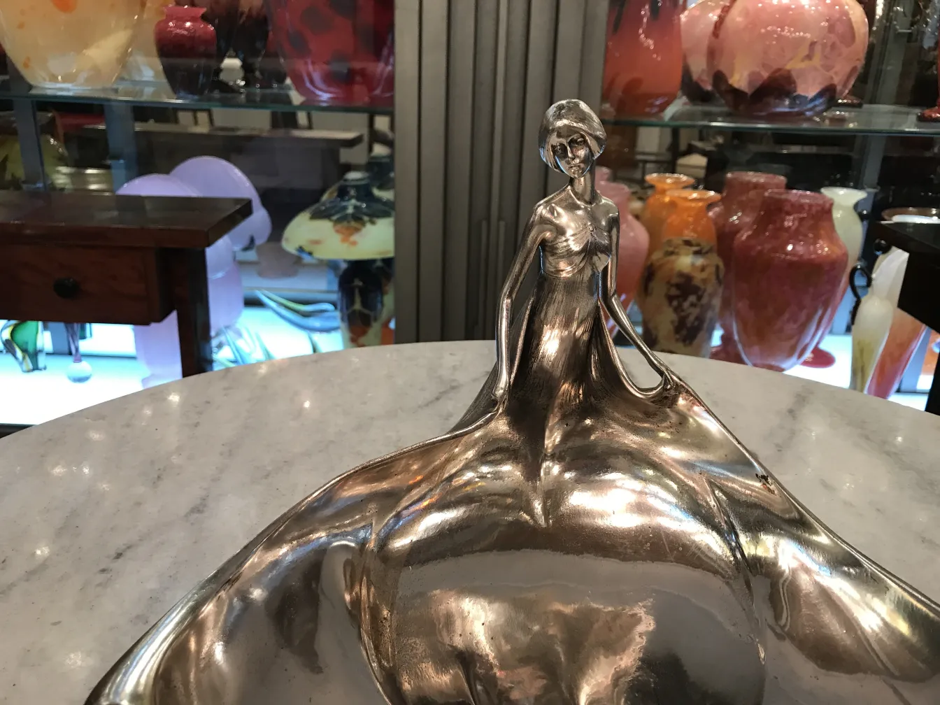 antico vassoio per carte con design elegante e figura femminile, circondato da oggetti decorativi colorati