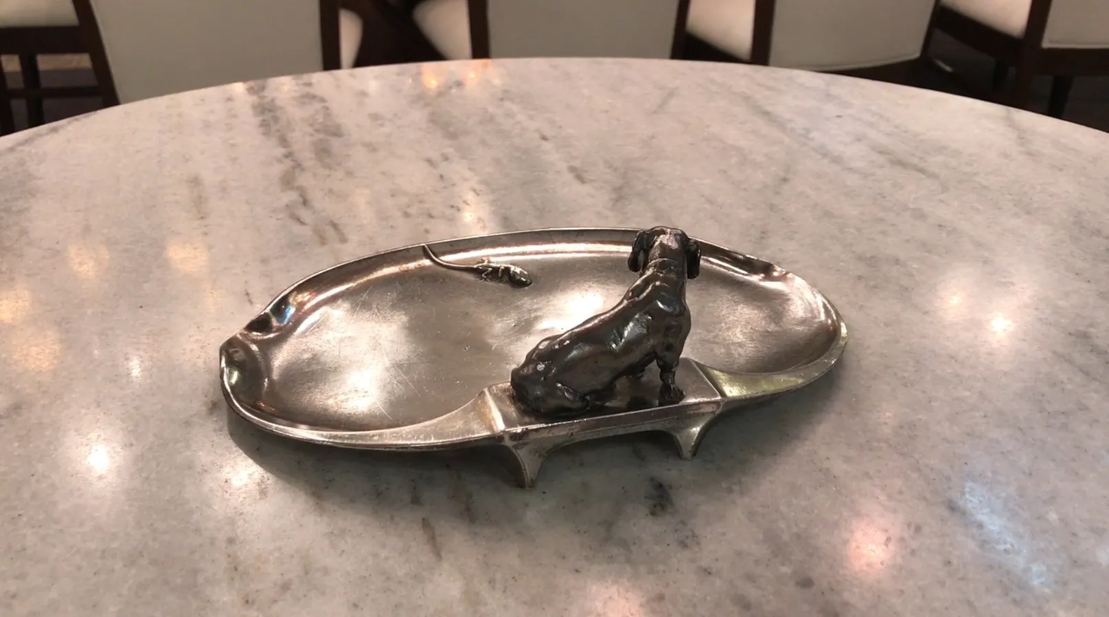 Antique card tray WMF featuring a dog and mouse figurine, on a marble table.