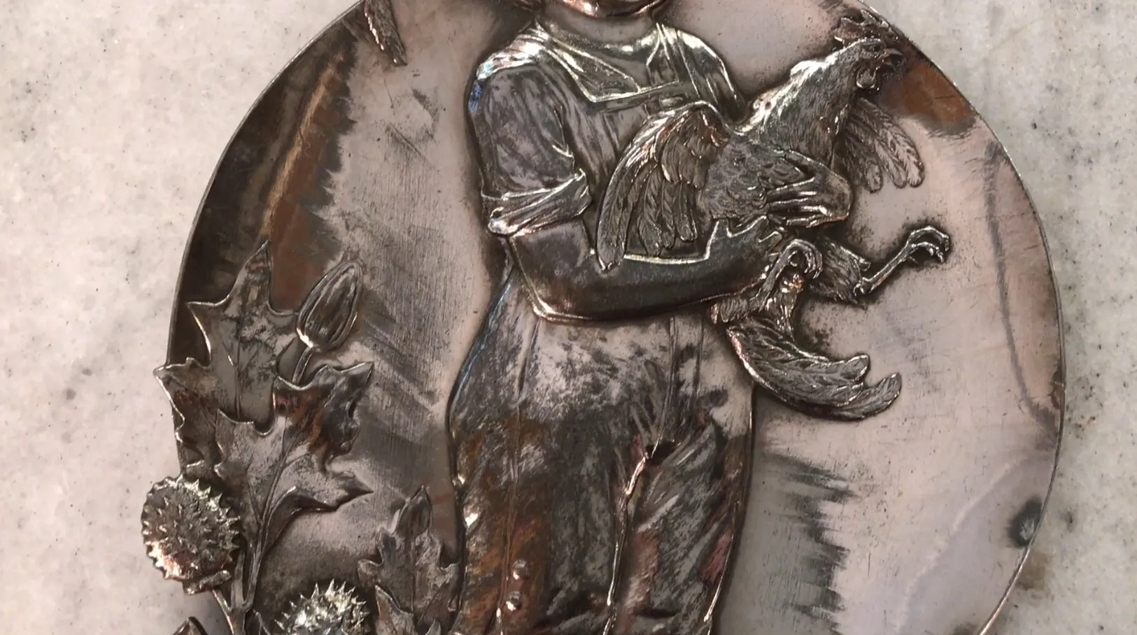 plateaux de carte antique WMF représentant un enfant tenant un coq, ornements floraux sur le bord.