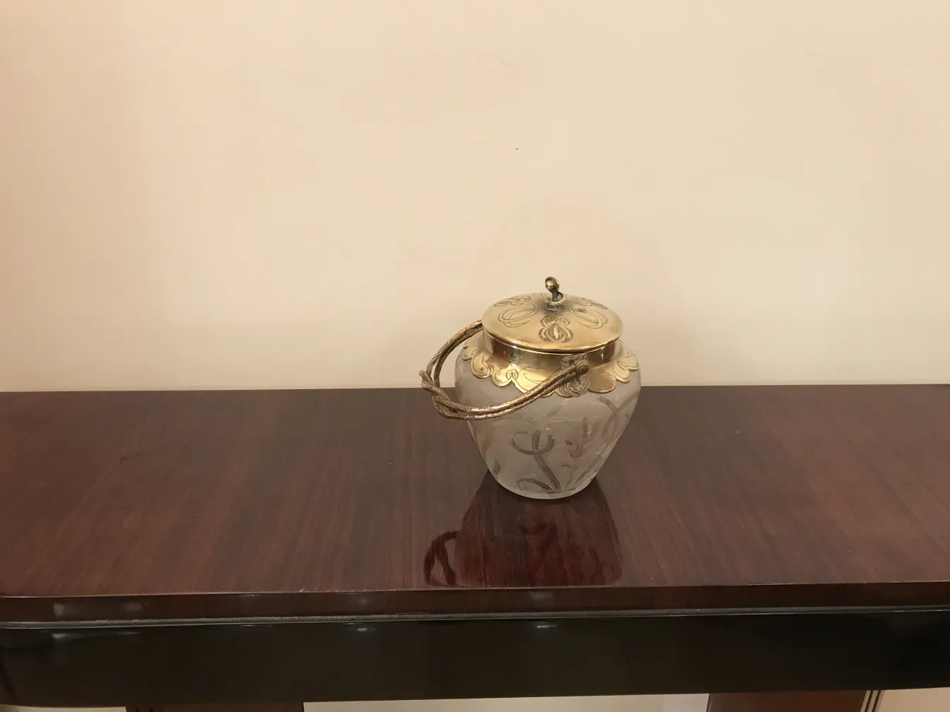 Caramelera antigua con tapa decorada, sobre mesa de madera