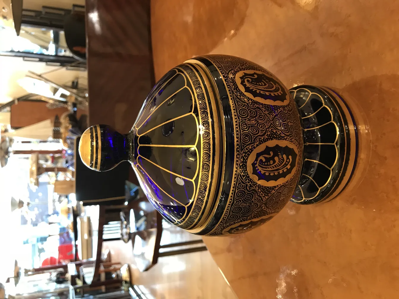 caramelera antigua con tapa de diseño azul y dorado, decoraciones sutiles, entorno de antigüedades