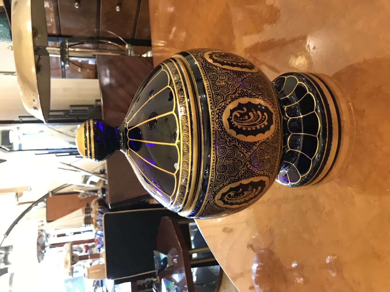 caramelera antigua decorativa con patrones en azul y oro sobre una mesa brillante