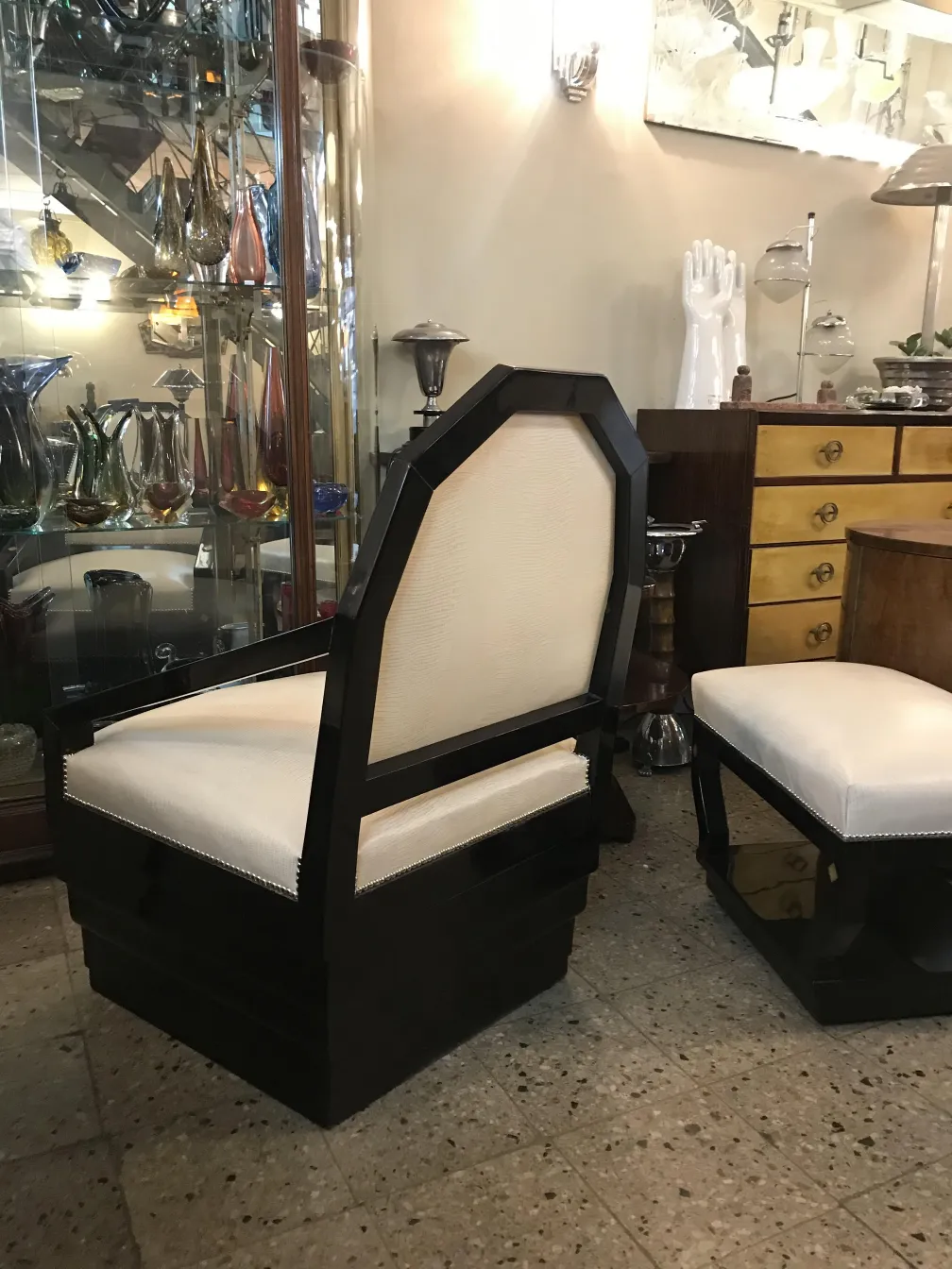 Poltrona antiga com um design único e elegante, cercada por outras antiguidades em um ambiente clássico.