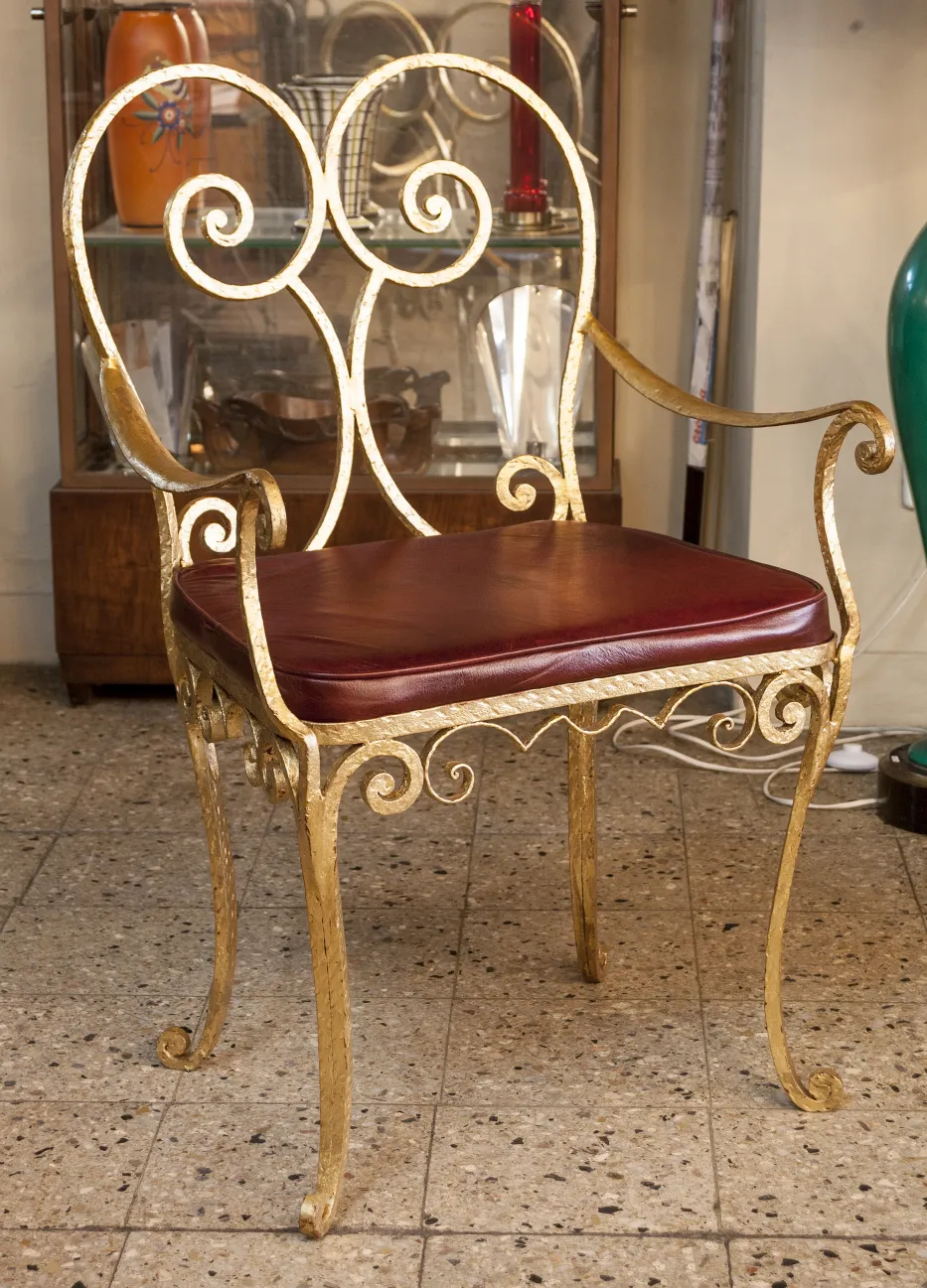 Fauteuil ancien avec design en fer doré et coussin bordeaux