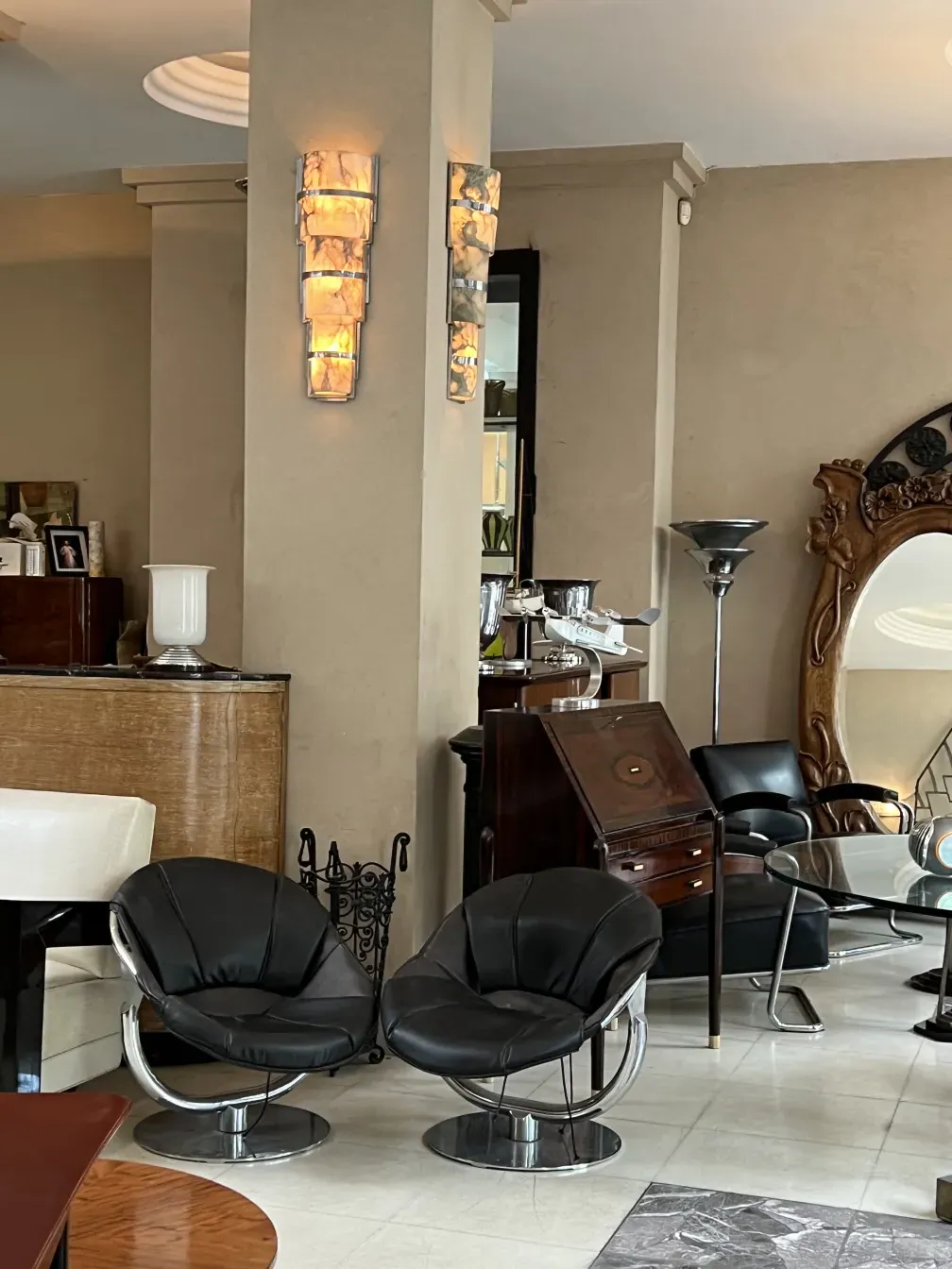 Dos sillones antiguos en un ambiente elegante con lámparas y decoración variada.