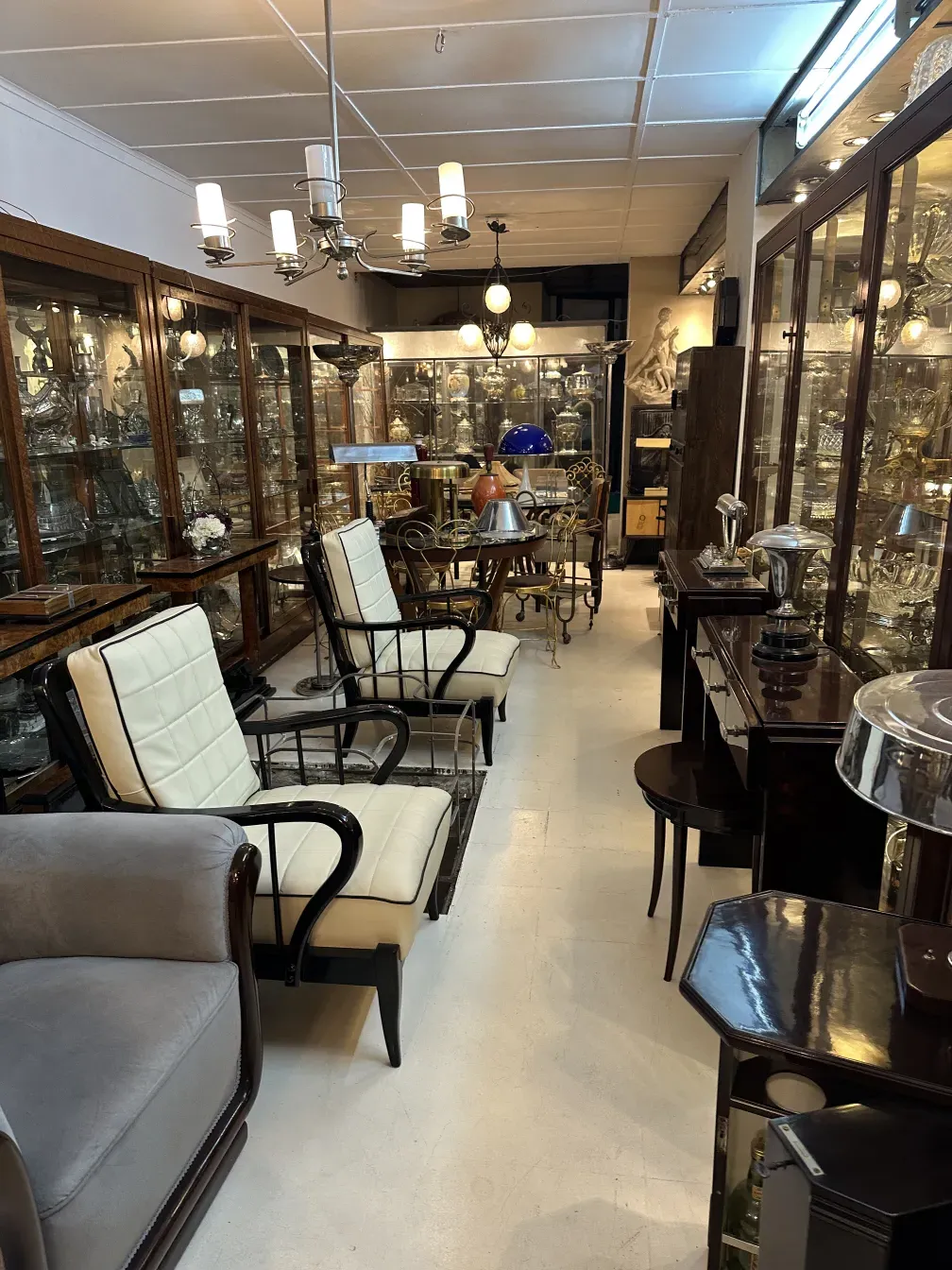 two antique armchairs by Paolo Buffa in a room with display cabinets