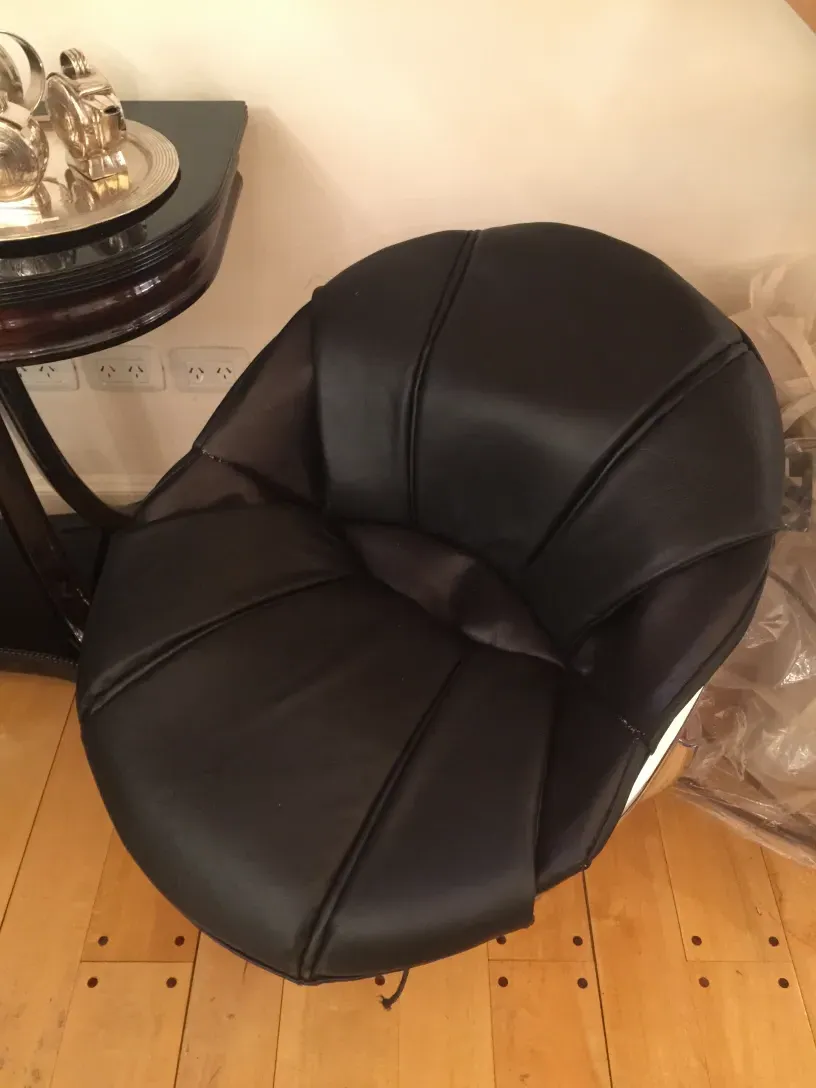 Sillón redondo negro en una habitación con mesa antigua.