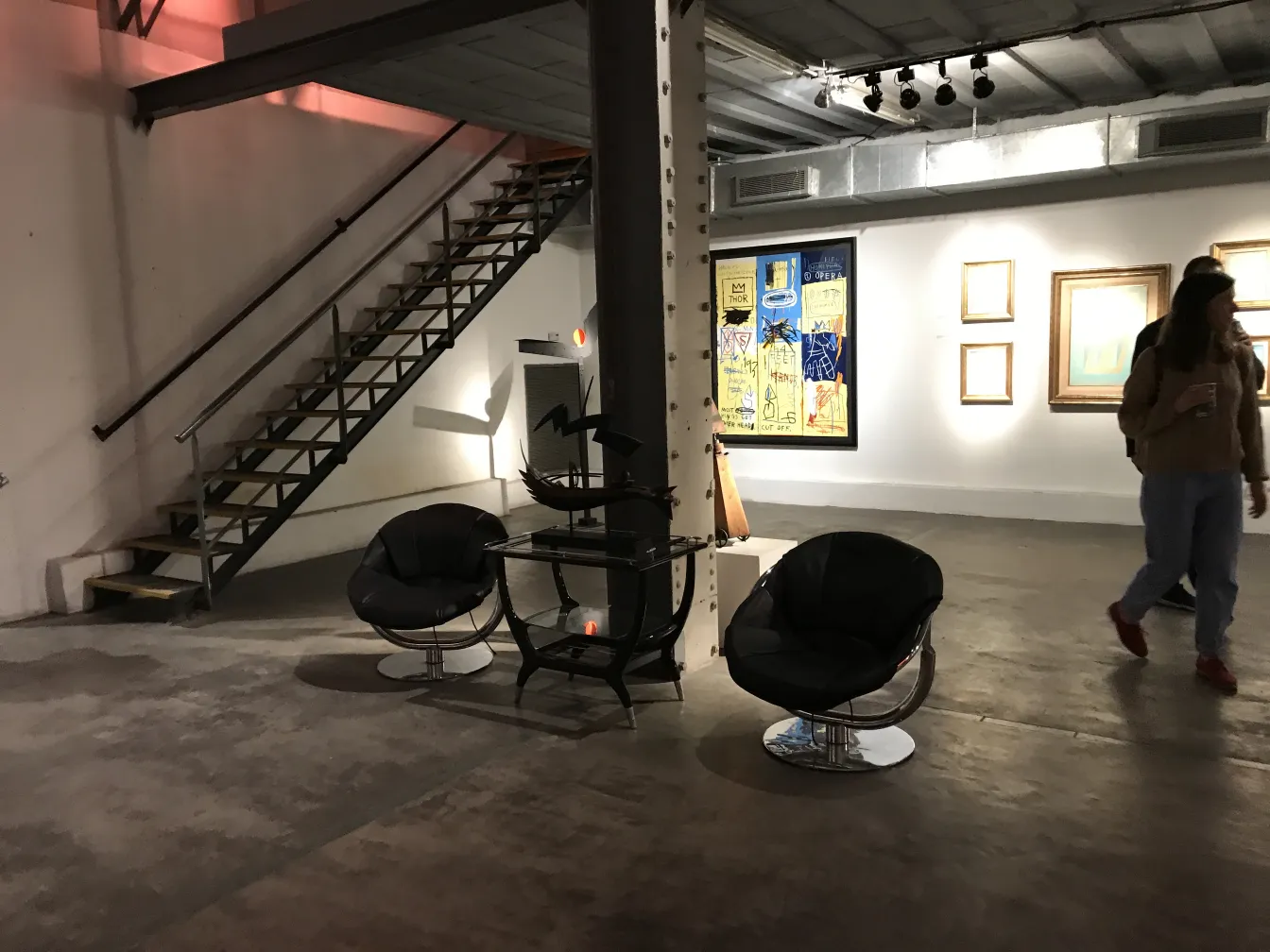 Two antique armchairs in an artistic setting, with stairs in the background.
