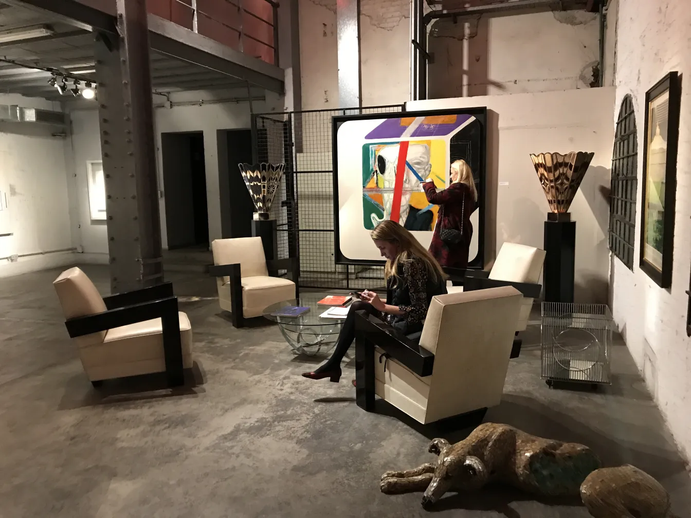 duas poltronas antigas em uma galeria com mesa de vidro