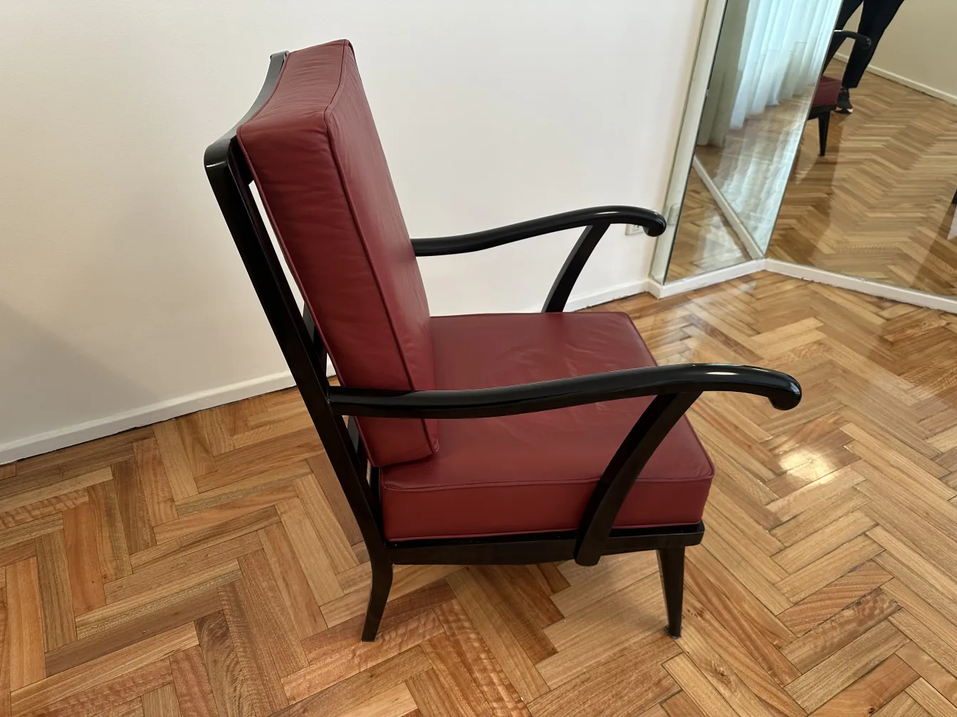 Duas poltronas antigas com estofamento bordô, bem conservadas e design elegante em um ambiente acolhedor.