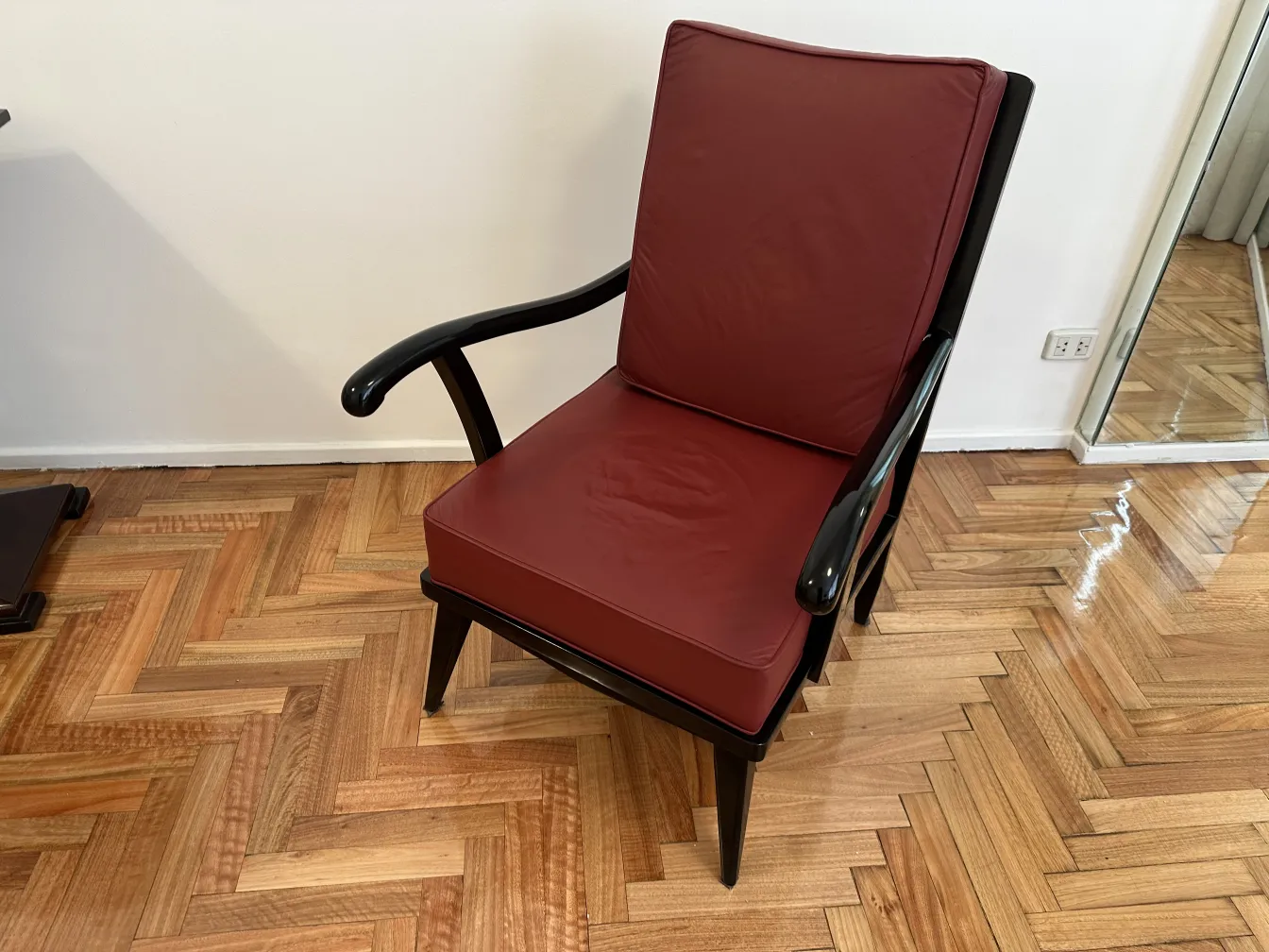 Two antique armchairs in burgundy color with arms.