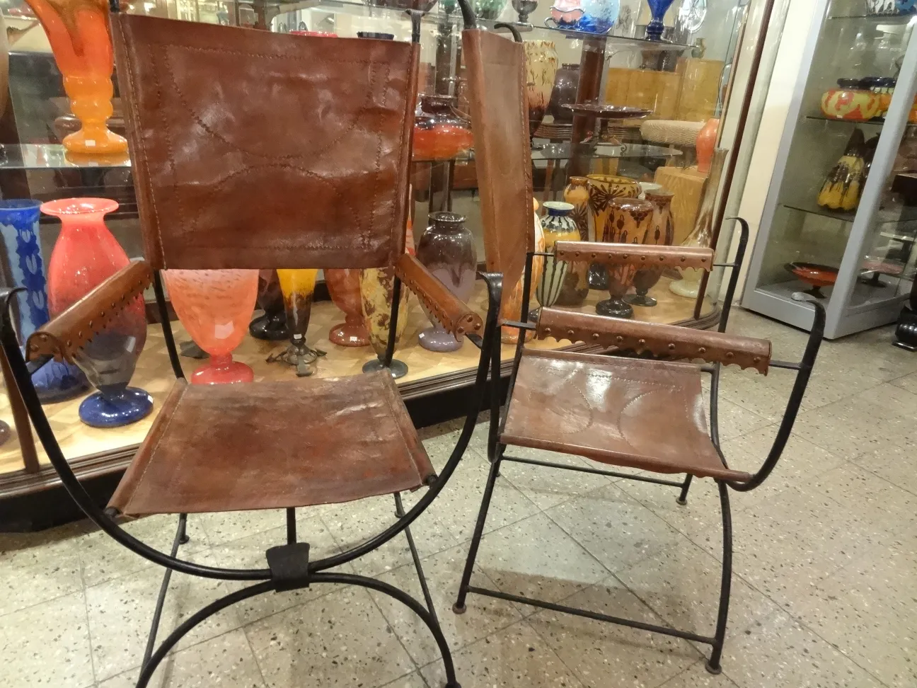 due poltrone antiche in pelle in un ambiente colorato con anfore