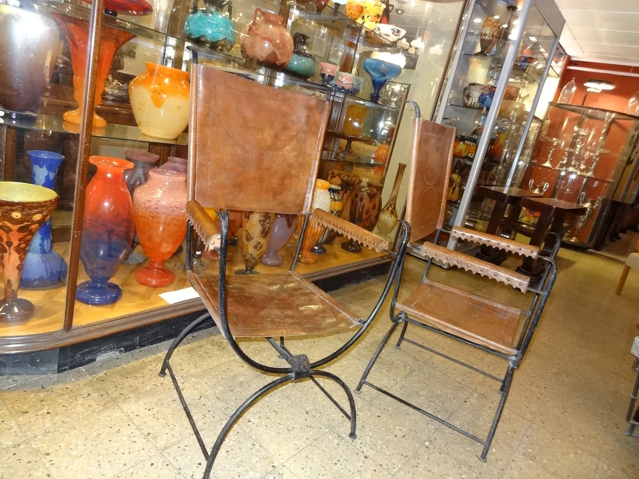 deux fauteuils anciens avec des détails complexes, entourés de vases en verre colorés