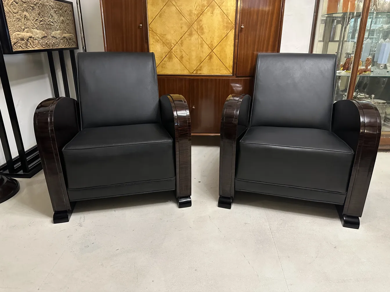 दो पुरानी कुर्सियों का दृश्य, गहरे रंग और सुरुचिपूर्ण डिज़ाइन के साथ, एक शास्त्रीय परिवेश में।