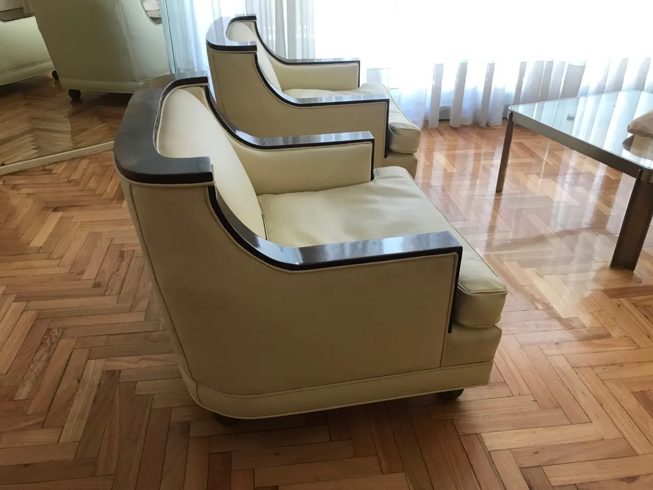 Vue latérale de 2 fauteuils anciens dans une pièce lumineuse avec parquet.