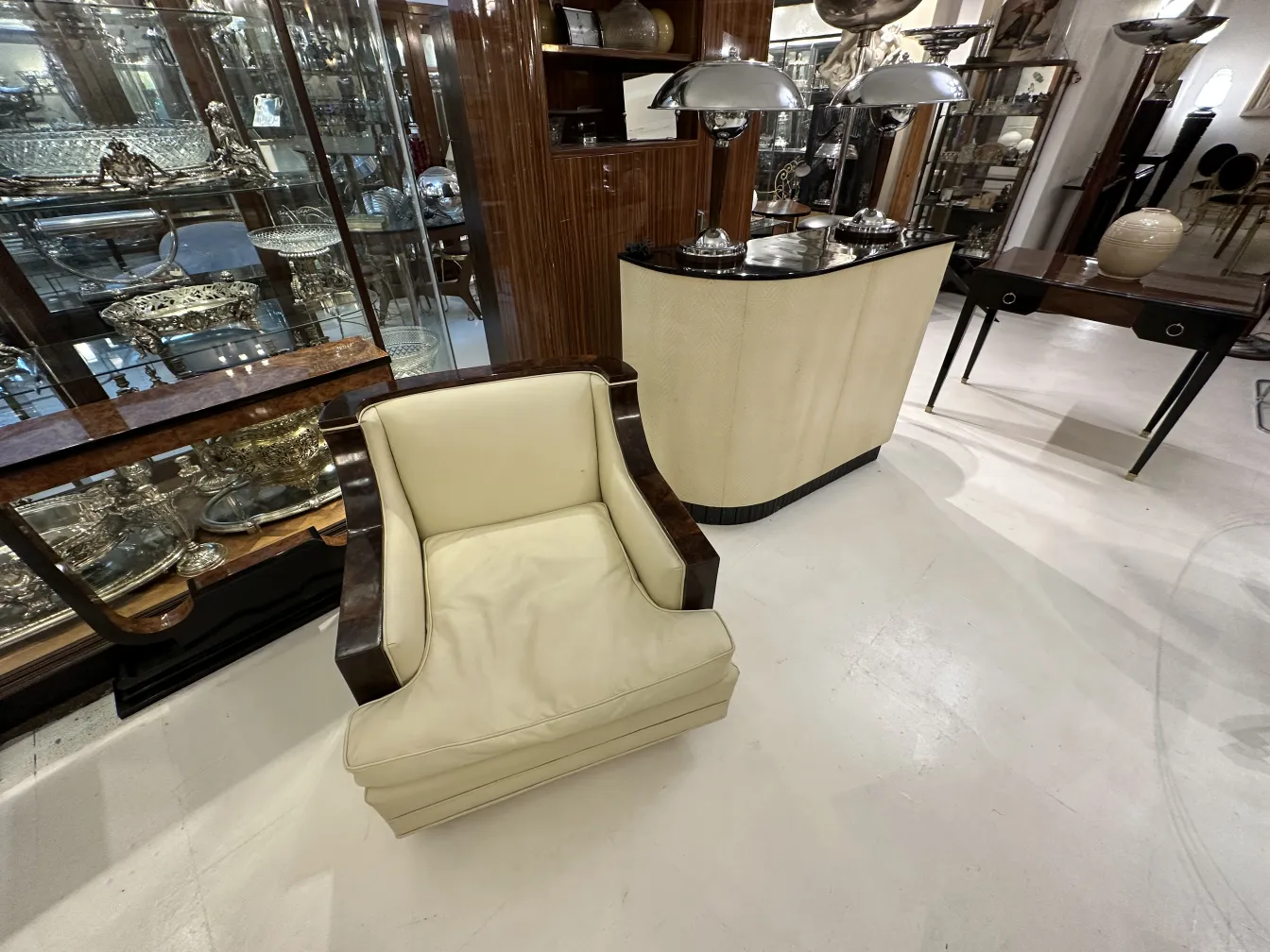 Visão de 2 poltronas em ambiente de antiguidades, elegantes em cor creme.