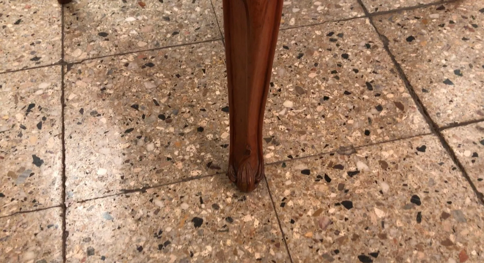 Detail eines antiken Armlehnstuhlbeins im art nouveau Stil, mit dekorativen Mustern.