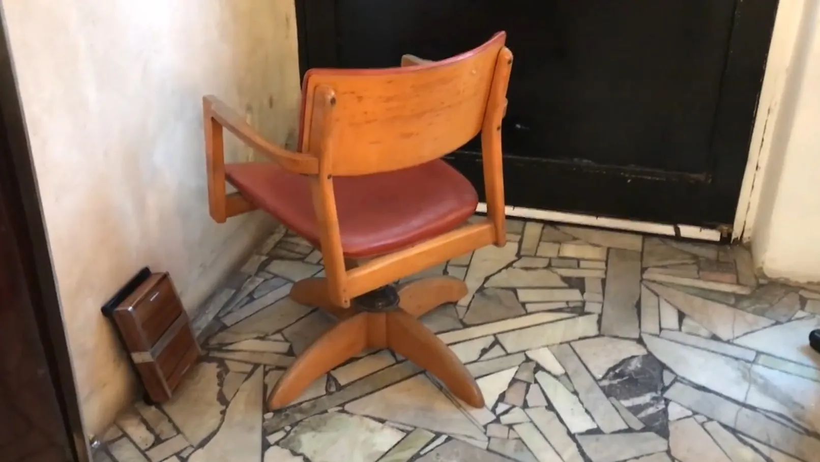 古いオフィスチェアが明るい壁の部屋にある、温かい雰囲気。