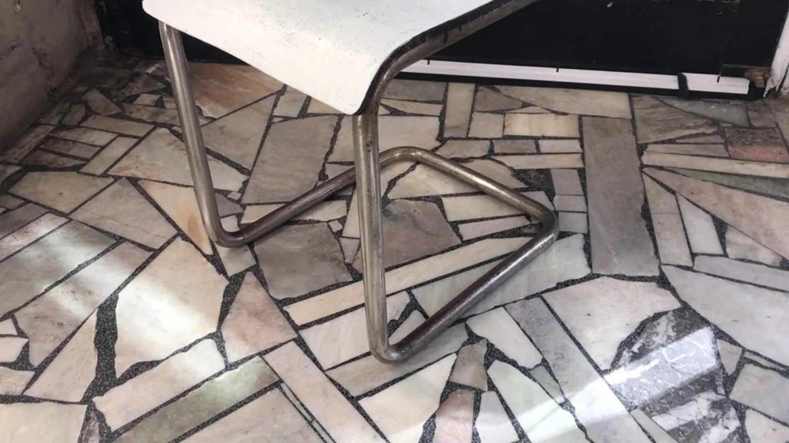 Antiker Bürosessel mit Metallbasis in neutralem Umfeld.