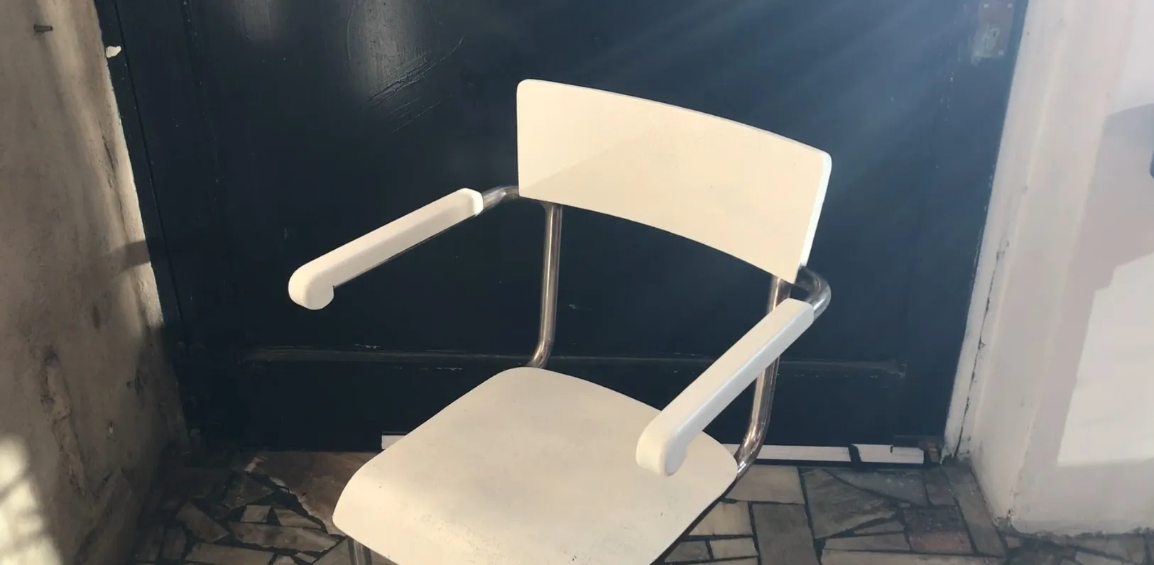 sillón de escritorio antiguo, blanco, con brazos, frente a una puerta oscura