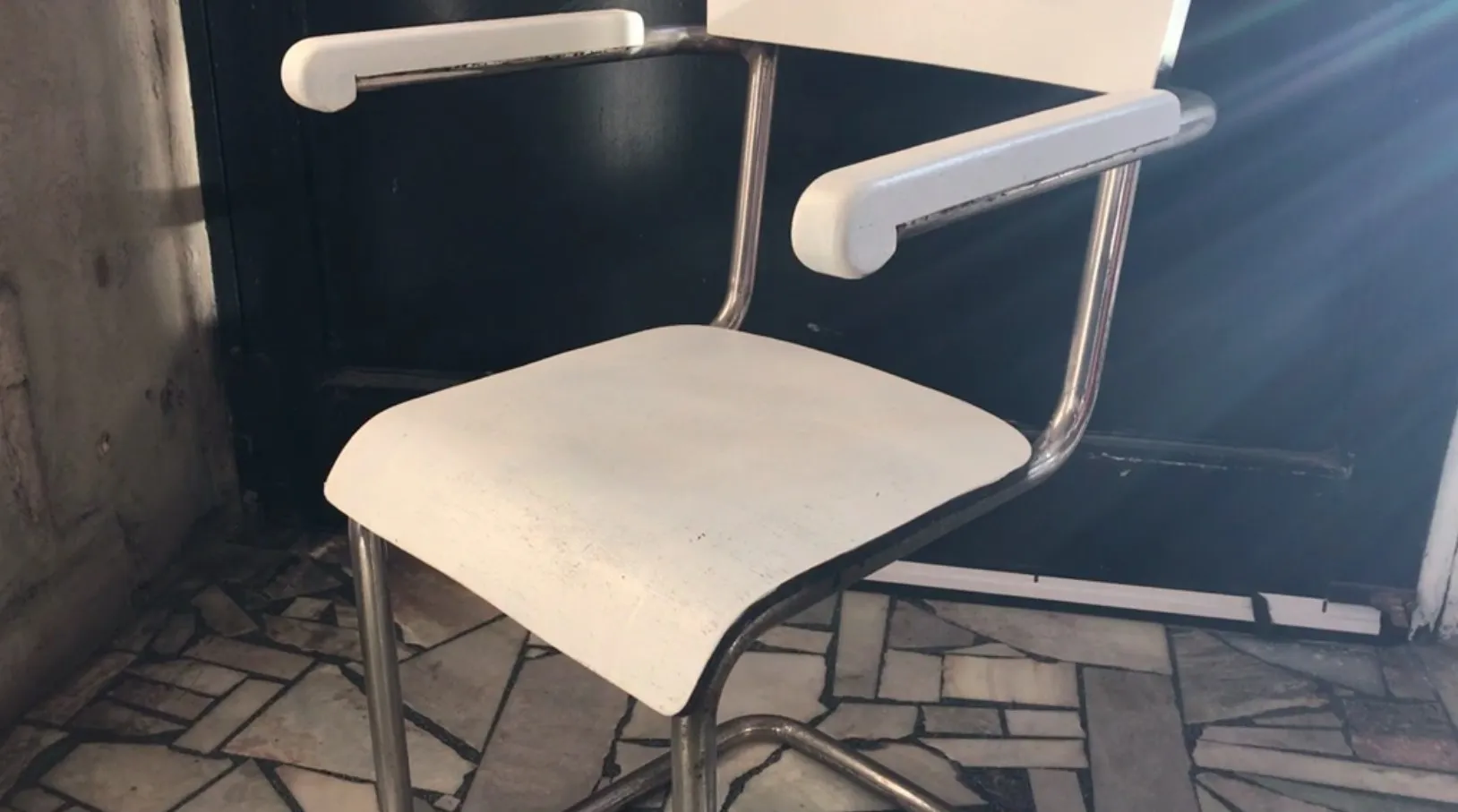 poltrona da ufficio antica di colore bianco con design elegante in un ambiente con muro di pietra